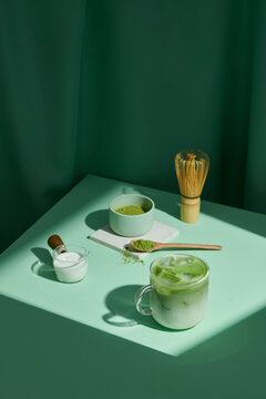 Matcha latte and accessories for making on green background