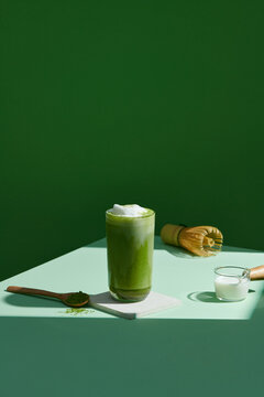 a Glass of Ice matcha latte on the table with Ingredients for making