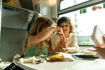 Sibling doing craft during their train ride
