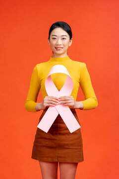 Beautiful woman holding pink cancer ribbon symbol over red