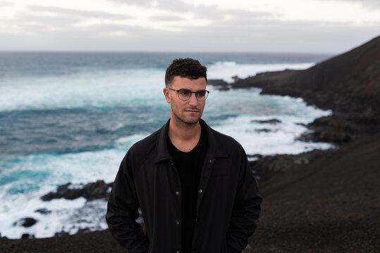 Portrait of a man staring into nothingness with the sea behind him