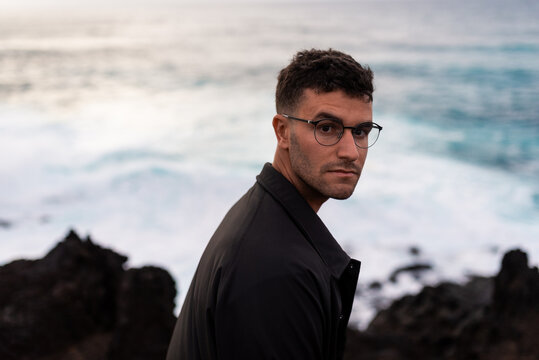 Portrait of a model facing the camera with a rough sea behind him