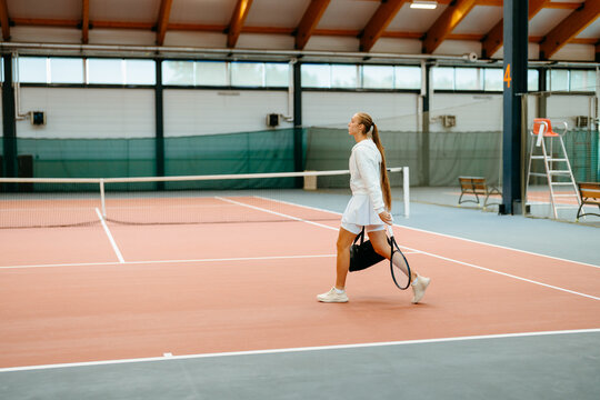A woman walks on a tennis court