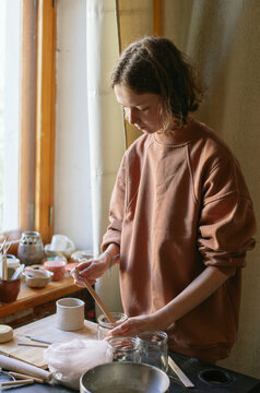 
Girl stirs enamel to coat pottery