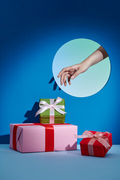 A woman hand taking a beautiful gift box from a big stack of gifts
