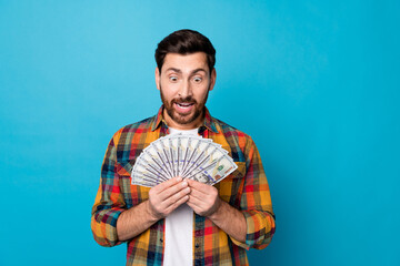 Photo of astonished funny man with beard dressed plaid shirt staring at bunch of dollars in hands...