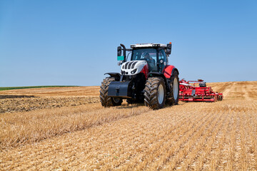 The tractor works on the stubble with reduced tillage