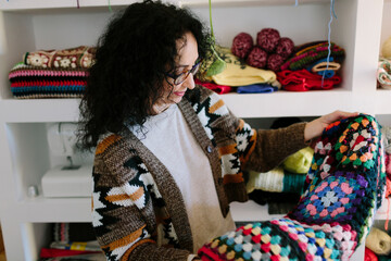 A woman looks at her handmade knitting creations