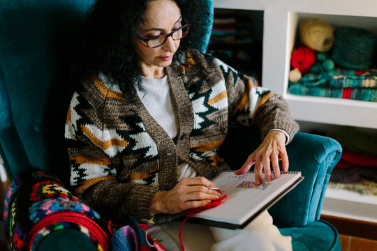 A woman is reading while sitting on an armchair
