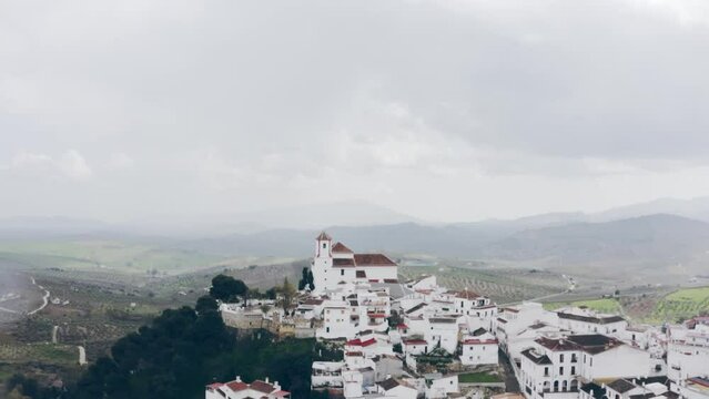 Drone of the white town with church at the top of the hill, Alozaina, Andalusia, Spain