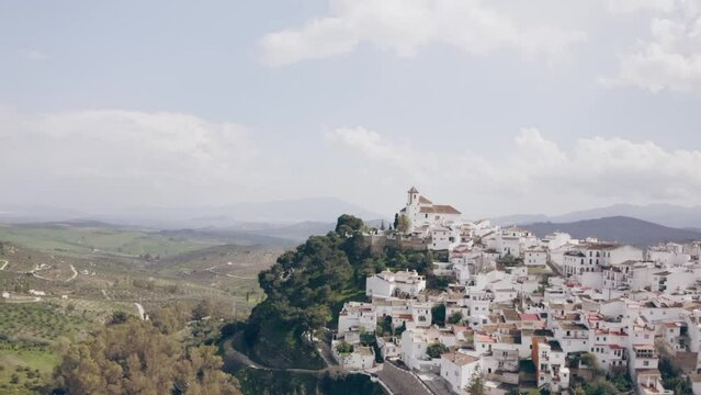Drone view of the white town with the church at the top of the hill, Alozaina, Andalusia, Spain
