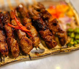 Homemade beef Satay marinated with spice and sweet soy sauce, coriander beef satay, served on plate with onion, chilli, soy sauce and tomato