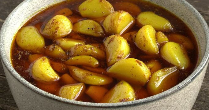 Garlic pickle in a bowl. Spicy, tangy and mouth watering side dish from India. Table spin.