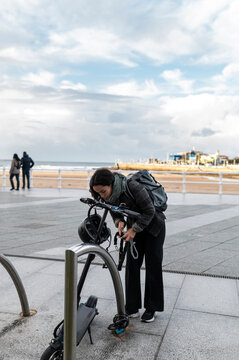 Businesswoman parking e-scooter in city steet in winter