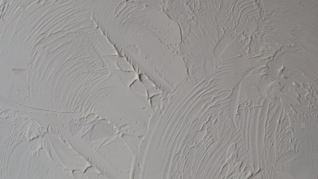 Applying decorative putty. White abstract texture of surface covered with putty. textured background of filler paste applied with putty knife in irregular dashes and strokes. Rough surface plaster