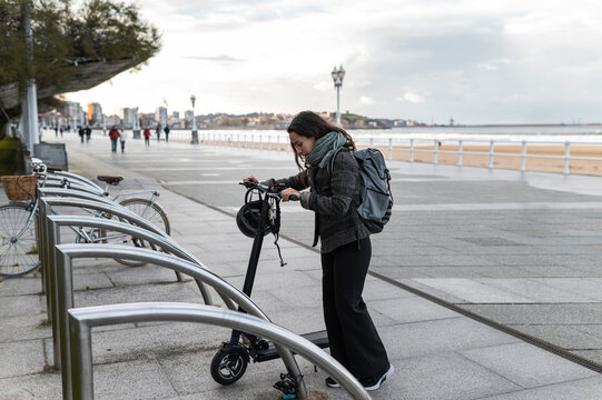 Woman parking electric scooter in city steet