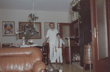 1986. Father and son pose for a photo in the living room of their home