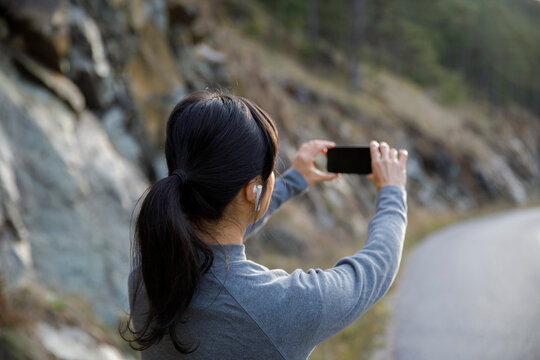 Woman photographing scenery on smart phone