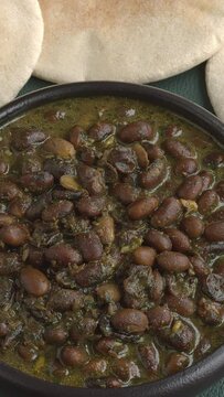 Black soybean curry. Some pita breads on the side. Table spin. Vertical video;