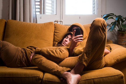 Chilling couple using mobile phone merged with sofa