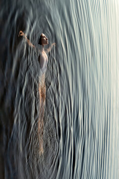 Ballet dancer floating on water surface outdoors