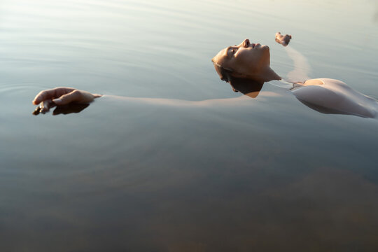 Ballet dancer floating on water surface outdoors