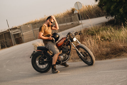 A man with his motorcycle with his hand on his head