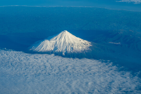Snow covered mountain as seen from window seat on flight on plane.