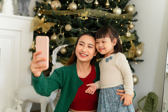 mom and with phone in hand sit on floor with christmas decoration