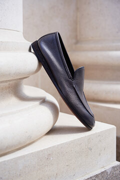 Stylish men's shoes stand on a column pilaster