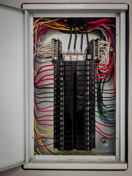 Inside of an home electricity breaker box with many colorful wires