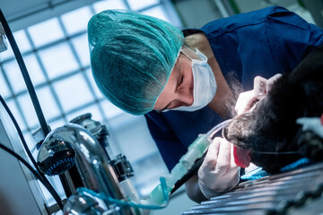 Bent woman vet cleaning teeth of dog on table with tool