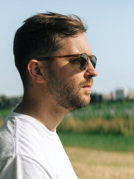 Contemplative Young Man with Sunglasses Outdoors in Sunshine