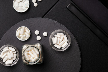 White colored nutritional supplements  in jars from above on a black desk on a black background....