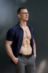 A photo of a confident, fit man wearing glasses and an open shirt. He poses with his hands on his hips against a neutral background, projecting strength and determination.