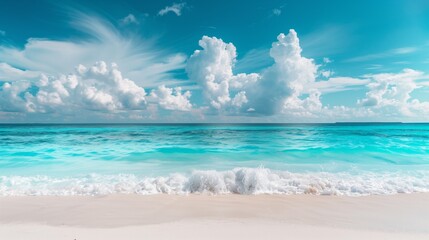 A tropical ocean beach landscape with bright blue water and waves reaching the sand. Beautiful blue sky and clouds.