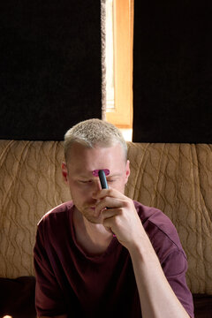 A young man uses a microcurrent device while working