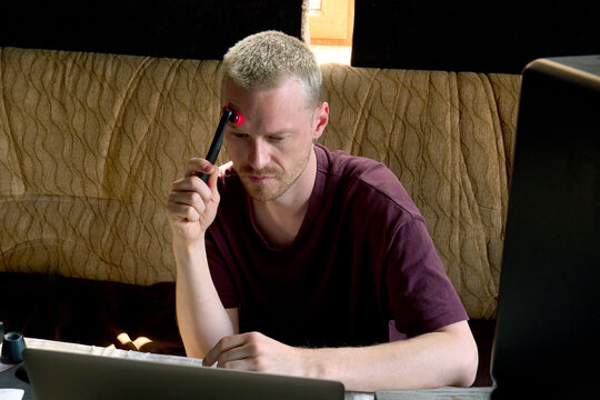 A young man uses a microcurrent device while working
