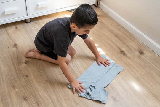 Young Boy Folds T-Shirt Independently, Breaking Gender Norms.