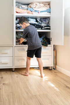 Young Boy Selects Outfit from White Wardrobe.