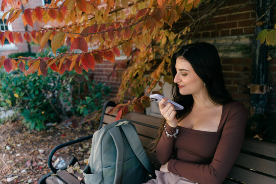 young student sitting bench talking on phone 