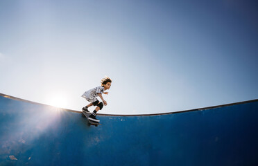 Kid with skateboard on ramp in skatepark