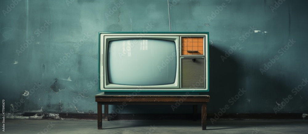 Poster an analog television is placed on a table in front of a wall. the rectangle display device shows tin