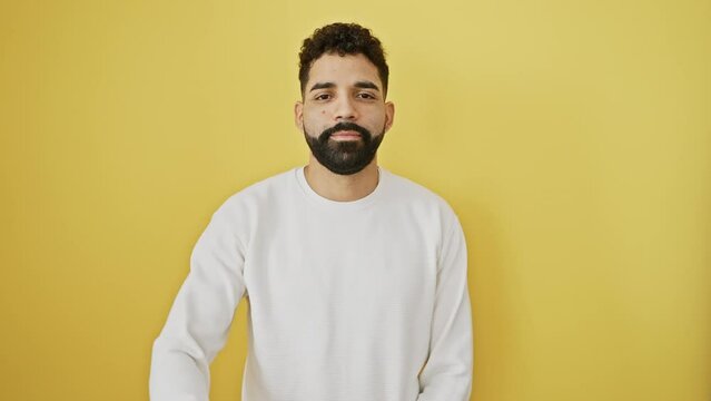 Cheerful young man does a winning 'ok' sign with his hand against a bright yellow background. radiating confidence, he shows success with a wide smile.