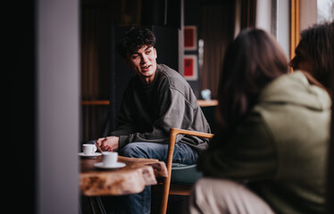 Group of young friends having a relaxing time and conversations over coffee in a cozy home setting.