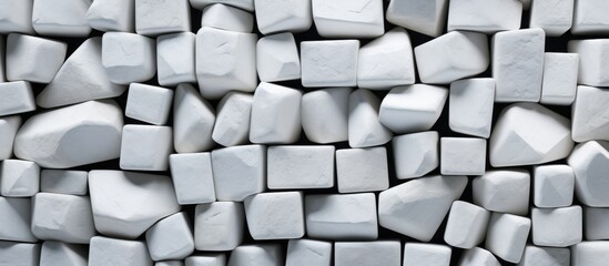 An upclose shot of a stack of white rectangular cubes, resembling bricks, with a grey wall as background. A product made of building material, used for flooring or walls with a pattern
