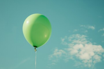 Obraz premium Vibrant green balloon representing mental health awareness floating against a soft blue sky creating a hopeful message of exploration and understanding