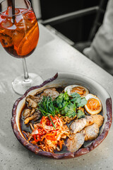 Poke Bowl in a beautiful bowl with a glass of cocktail on a light table outdoors