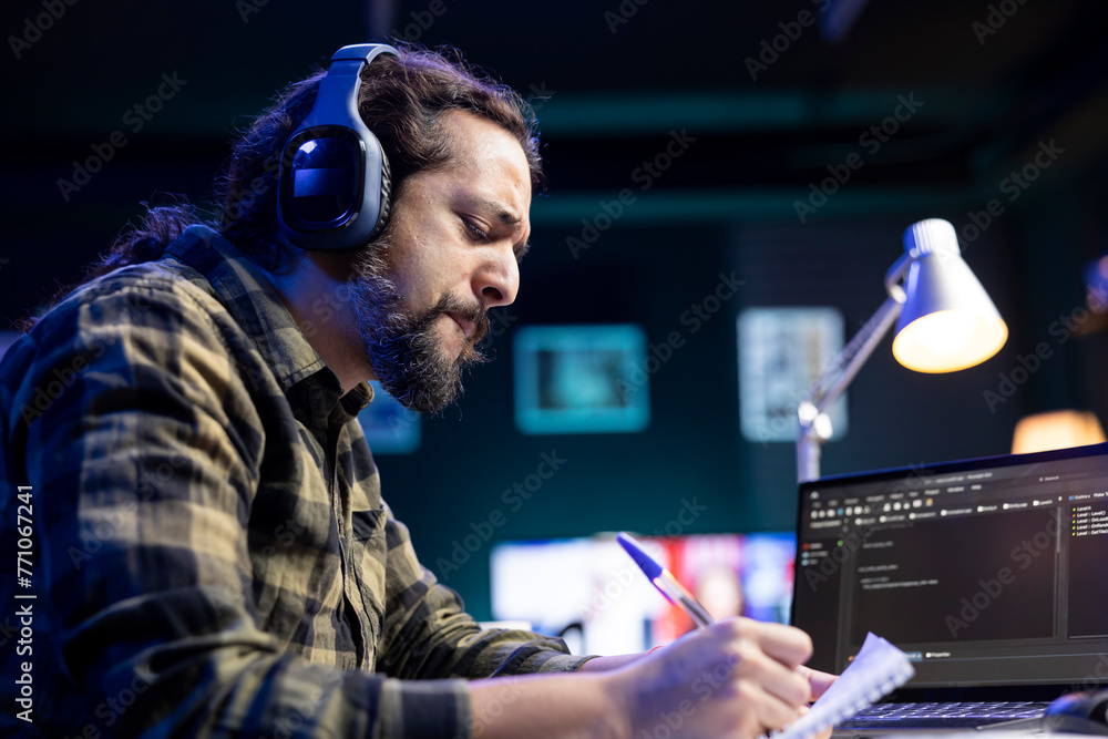 Poster focused man with headset, managing software and programming code on laptop. skilled male programmer 