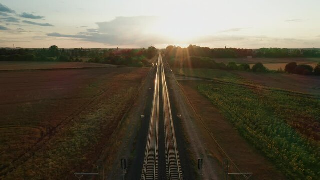Last rays of warm setting sun illuminate long railway. Railroad illuminated by golden light creates picturesque scene as sun descends in sky